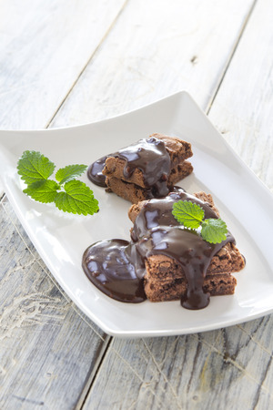 Brownies with chocolate sauce on a white plateの写真素材