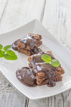 Brownies with chocolate sauce on a white plateの写真素材