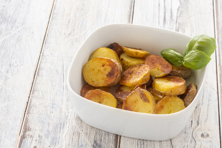 Roasted Potatoes in a bowl on a white tableの写真素材