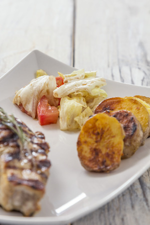 Fillet with fried Potatoes and salat on a white plate, shallow depth of fieldの写真素材