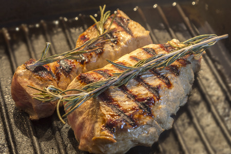 Two pieces of pork fillet in a grill pan with rosemary の写真素材