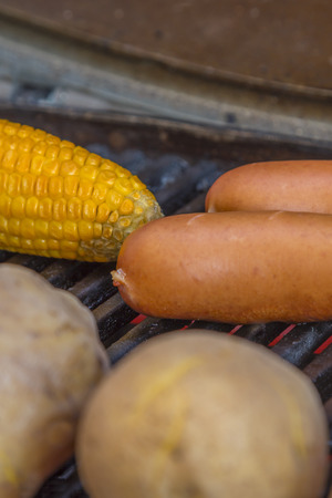 Potatoes Sausages and a corn cob and red pepper on a grillの写真素材