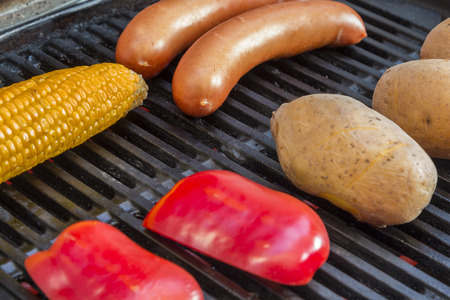 Potatoes Sausages and a corn cob and red pepper on a grillの写真素材