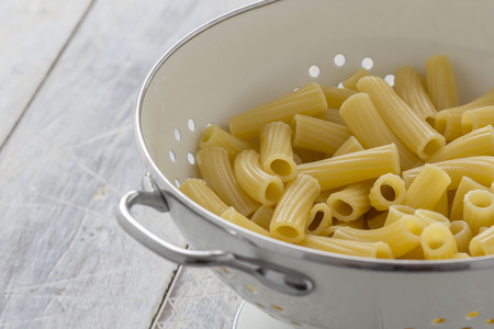 Frehs cooked Tortiglioni Pasta in a sieve on a tableの写真素材