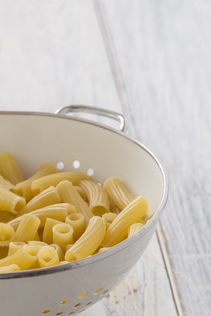 Frehs cooked Tortiglioni Pasta in a sieve on a tableの写真素材