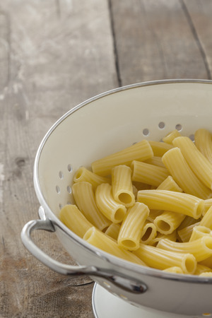 Frehs cooked Tortiglioni Pasta in a sieve on a tableの写真素材