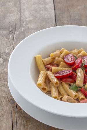 Tortiglioni Pasta with roasted chicken breast and tomatoes on a white plateの写真素材