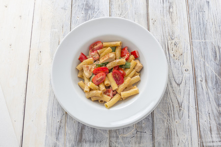 Tortiglioni Pasta with roasted chicken breast and tomatoes on a white plateの写真素材