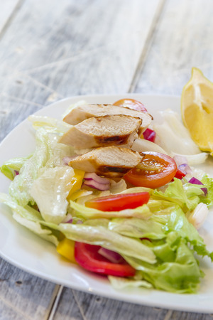 Green Salad with chicken breast filet, Tomatoes red and yellow pepper and red onions on a plateの写真素材