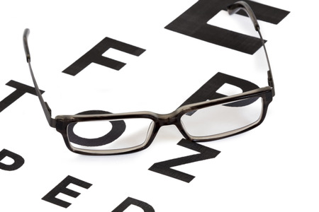 Modern retro looking glasses on an eyesight test chart isolated on white backgroundの写真素材