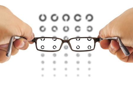 glasses beeing hold in front of an ring eyesight test charts isolated on white backgroundの写真素材