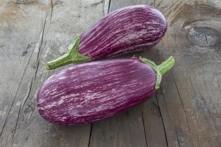 Two Violet Aubergine on a wooden rustic boardの写真素材