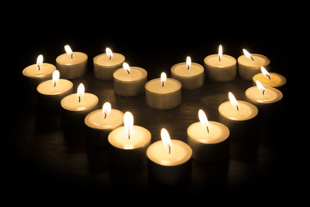 Tea Candles forming a heart shape on black backgroundの写真素材