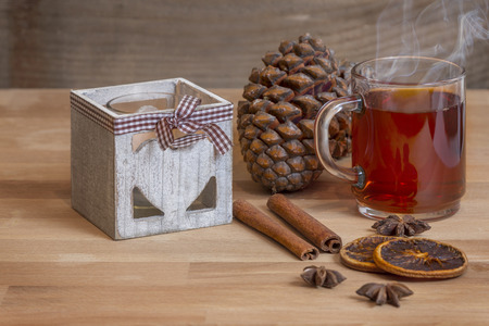 Glass of hot spiced wine with cinnamon oranges and star anise on rustic wooden tableの写真素材