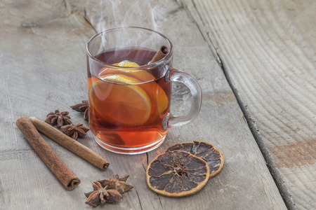 Glass of hot spiced wine with cinnamon oranges and star anise on rustic wooden tableの写真素材