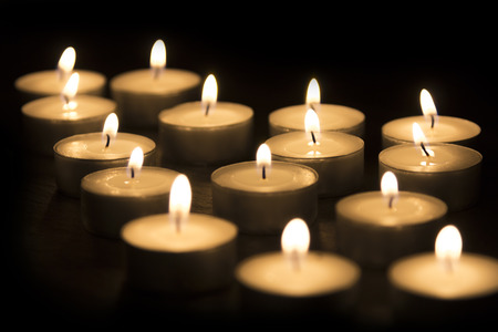 A Group of tea candles burning on a black backgroundの写真素材