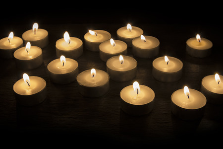 A Group of tea candles burning on a black backgroundの写真素材