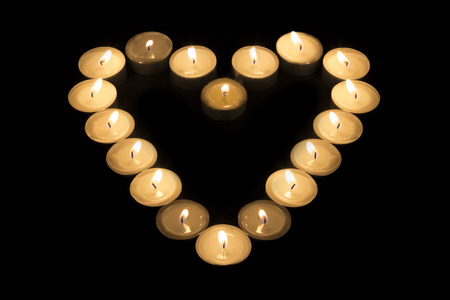 Tea Candles forming a heart shape on black backgroundの写真素材