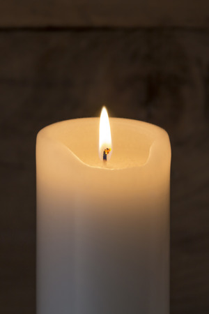 A WHite Candle burning on rustic wooden backgroundの写真素材