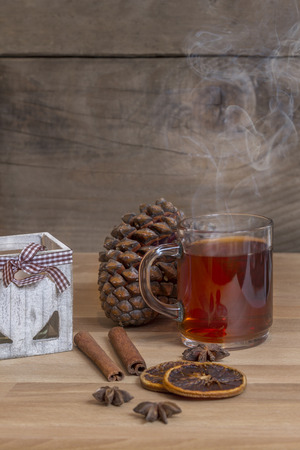 Glass of hot spiced wine with cinnamon oranges and star anise on rustic wooden tableの写真素材