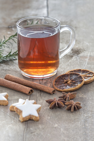 Glass of hot spiced wine with cinnamon oranges and star anise on rustic wooden tableの写真素材