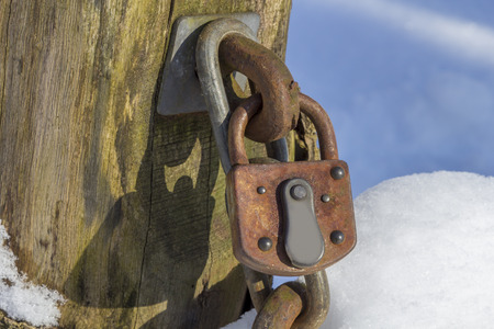 A Rusty Lock on a wooden pole with snowの写真素材