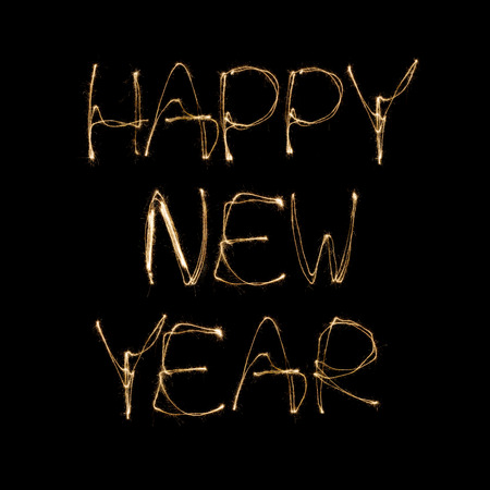 Happy new Year written with a sparkler isolated on black backgroundの写真素材
