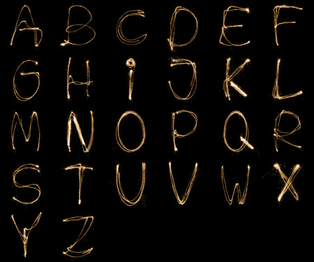 Alphabet written with a sparkler isolated on black backgroundの写真素材