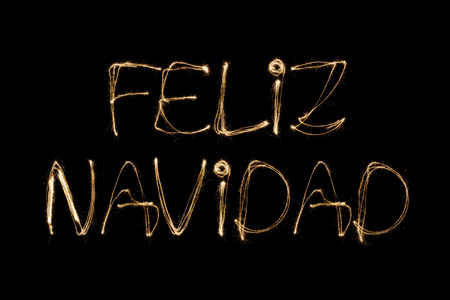 Feliz Navidad (Spanish Merry Christmas) written with a sparkler isolated on black backgroundの写真素材