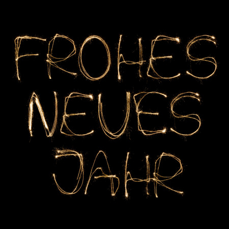 Frohes neues Jahr (German Happy new Year) written with a sparkler isolated on black backgroundの写真素材