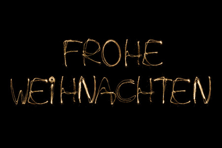 Frohe Weihnachten (German Merry Christmas) written with a sparkler isolated on black backgroundの写真素材