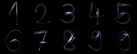 Collection of numbers written with a flashlighgt isolated on black backgroundの写真素材