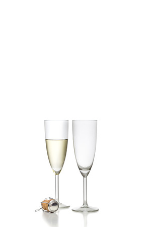 One filled and one empty glass of champagne isolated on white backgroundの写真素材