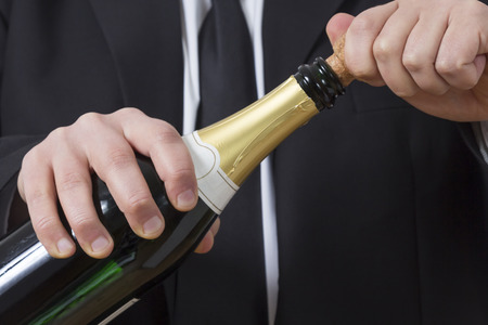 A man in a suit opening a bottle of Champagneの写真素材