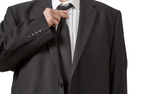 A Man in a black siut straightening his tie isolated on white backgroundの写真素材