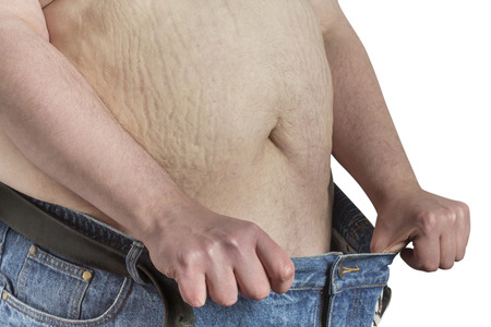 overweight shirtless Man stretching his blue jeans isolated on white backgroundの写真素材
