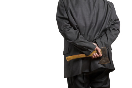 Man in suit hiding an axe behind his back isolated on white backgroundの写真素材