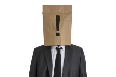 A Man in suit with a paper bag with an exclamation mark on his head isolated on white backgroundの写真素材