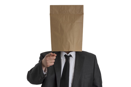 A Man in suit with a paper bag on his head pointing into the camera isolated on white backgroundの写真素材