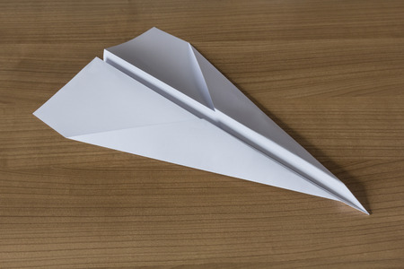Paper Airplane in claccic arrow shape on a wooden tableの写真素材
