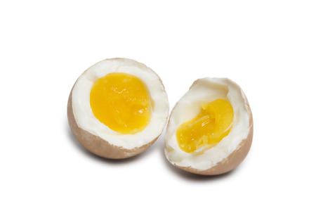 A Boiled egg in brown shell splitted in two halfs isolated on white backgroundの写真素材
