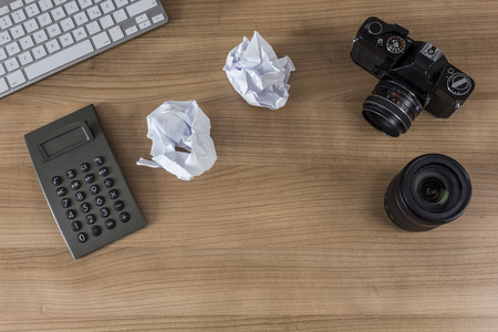 Modern keyboard, calculator, vintage camera and a pen on a wooden desktopの写真素材