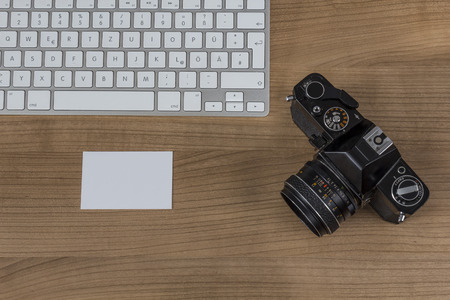Modern keyboard, camera and a business card on wooden Desktopの写真素材