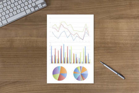 colorful diagrams on a wooden table with modern keyboard and silver penの写真素材