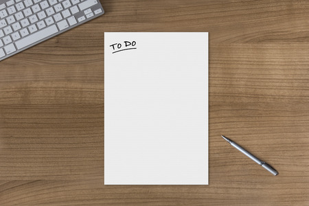 Blank sheet with the headline To Do on a wooden table with modern keyboard and silver penの写真素材