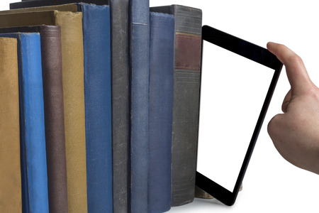 a hand pulling a tablet computer out of a row of books isolated on white backgroundの写真素材