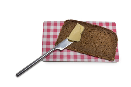 Bread with butter and knife on a board isolated on white backgroundの写真素材