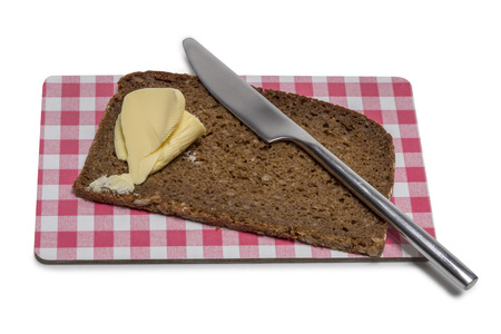 Bread with butter and knife on a board isolated on white backgroundの写真素材