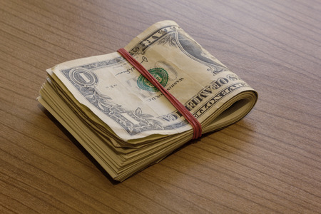 Bundle of dollar notes on a wooden tableの写真素材