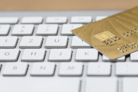 a golden credit card on a modern silver keyboardの写真素材